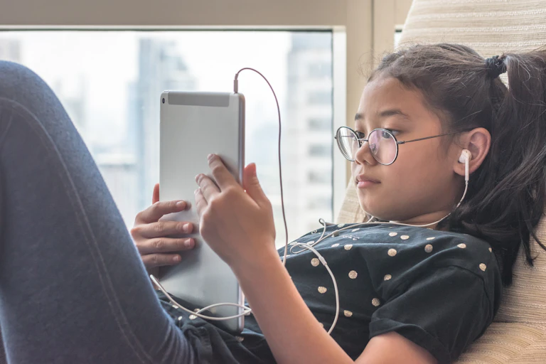 Girl looking at tablet with headphones in