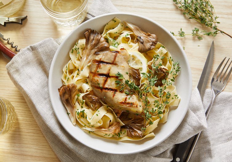Plate of pasta with a chicken fillet on top.