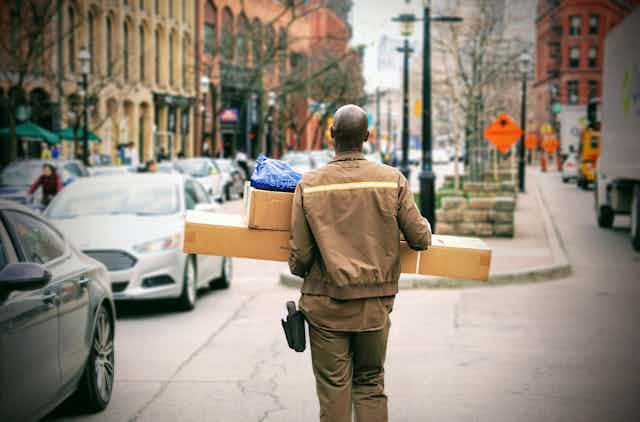 A delivery man carries packages.