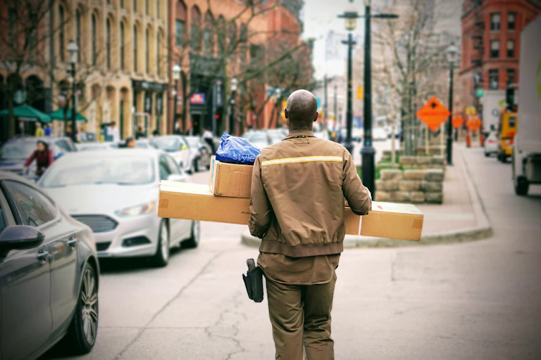 A delivery man carries packages.