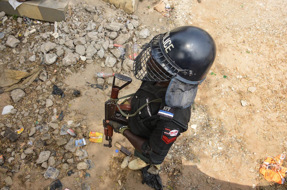 Picture from above of a police officer in a helmet and face shield holding a gun
