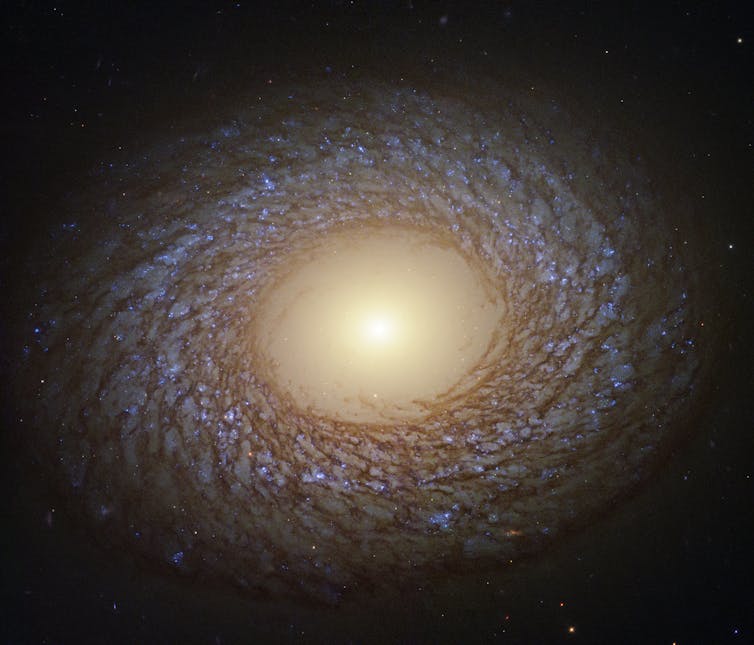 Computer enhanced image of a swirling galaxy with bright light at centre.