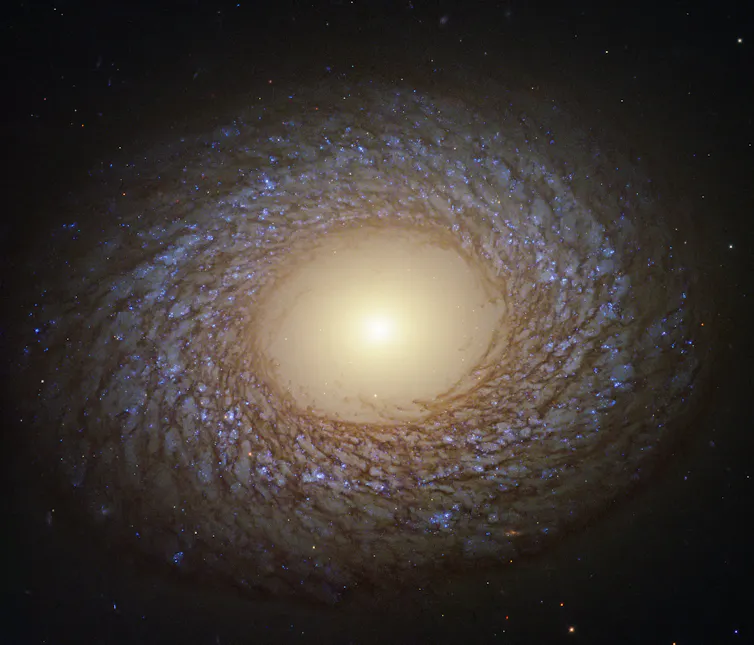 Computer enhanced image of a swirling galaxy with bright light at centre.