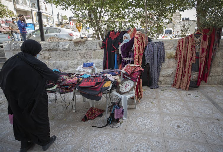 A woman displays a traditional Palestinian embroidery dress to a customer in Ramallah.