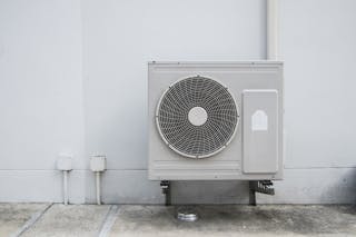 ファン付きの大きなエアコンプレッサーユニットがケーブルで家に取り付けられています。 I MAKE PHOTO 17/