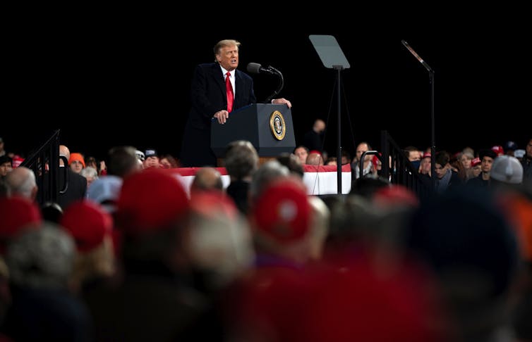 President Donald Trump speaks behind a podium.