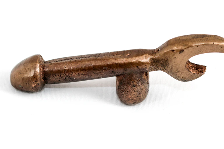 A brass bottle opener doubles as a phallic symbol.