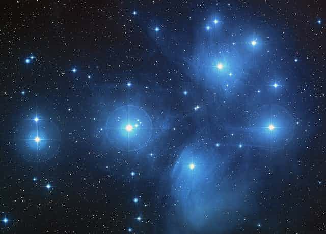Photograph of a cluster of several bright, blue-white stars.