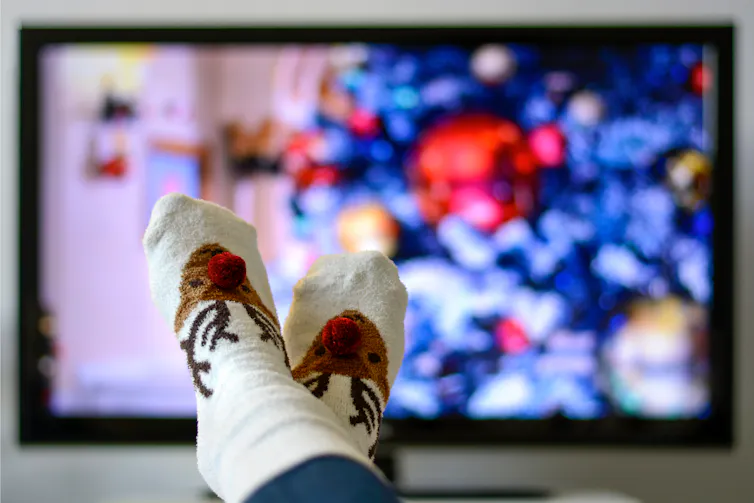 Feet in reindeer socks in front of a TV.