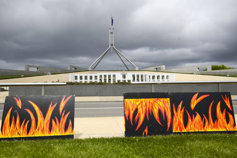 Posters depicting bushfire flames in front of Parliament House, Canberra