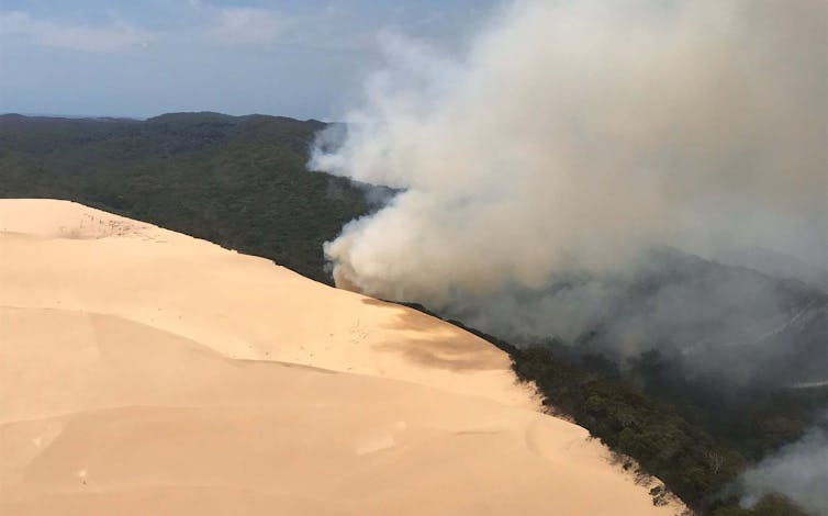 Smoke over bushland, beside sand