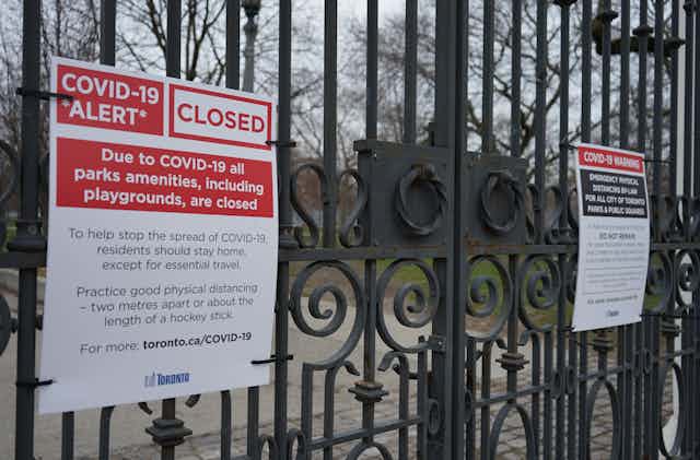 A sign on black metal gates that says COVID-19 ALERT CLOSED 