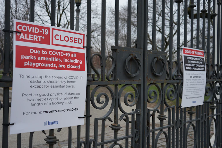 A sign on black metal gates that says COVID-19 ALERT CLOSED