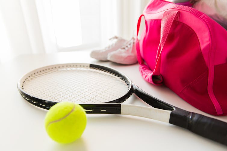Tennis bag, racket, ball and shoes lying around at home