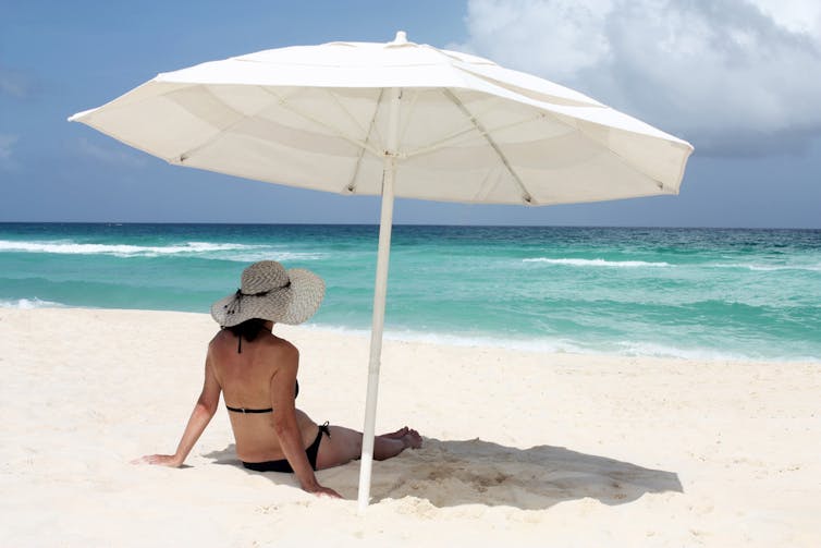 Woman sitting at the beach under an umbrella