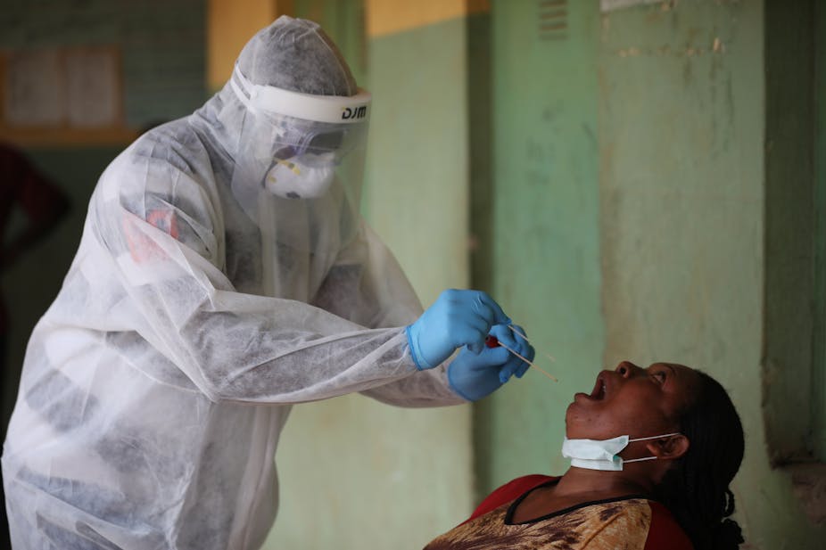 A health worker in white protective wears takes a swab from a woman during a community COVID-19 coronavirus testing campaign in Abuja, Nigeria