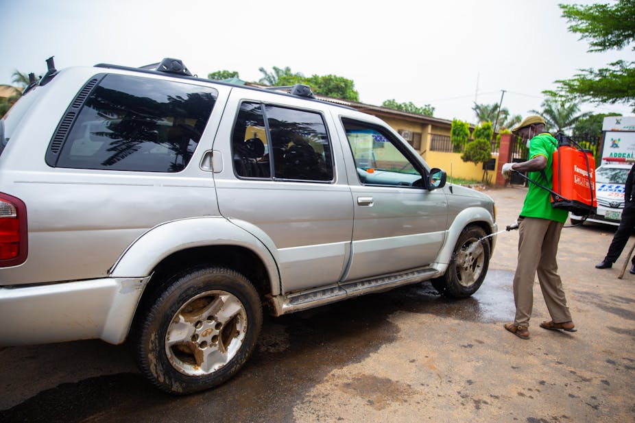A health worker disinfects a car coming into a warehouse where the Emergency Food relief is being packaged in Lagos 