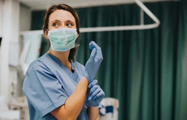 A nurse putting on latex gloves