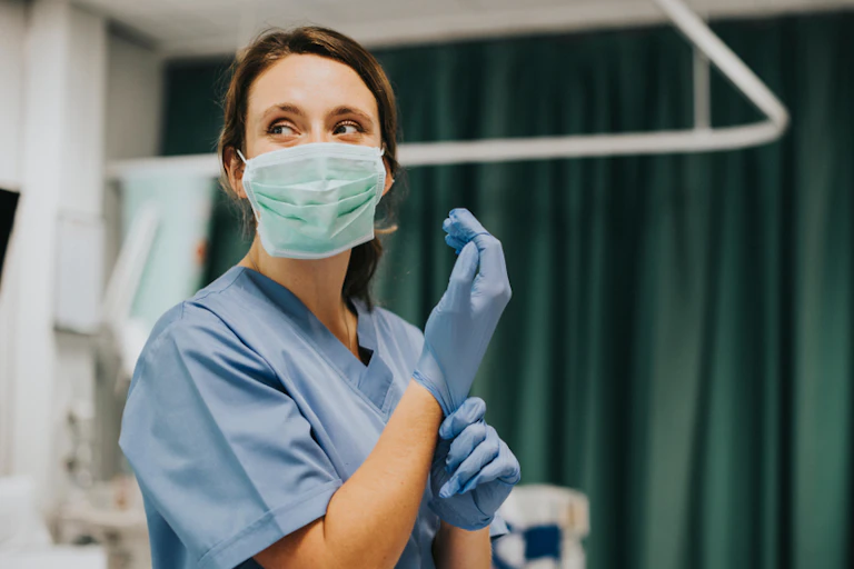 A nurse putting on latex gloves
