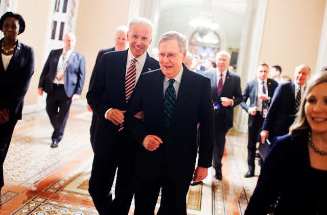 Biden and McConnel walk together, smiling