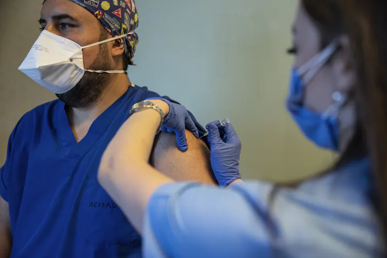 A health worker in scrubs being vaccinated