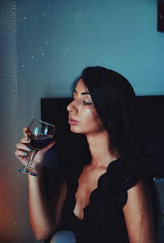 Woman is drinking a glass of red wine.