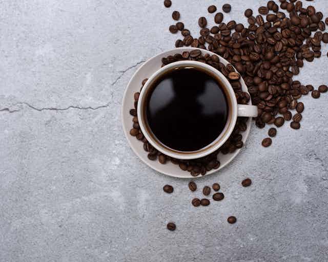 A photo of a cup of coffee sitting among coffee beans.