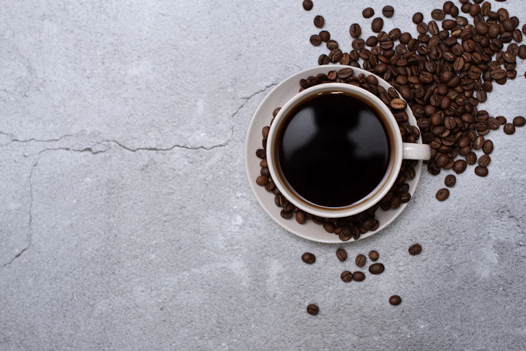 A photo of a cup of coffee sitting among coffee beans.