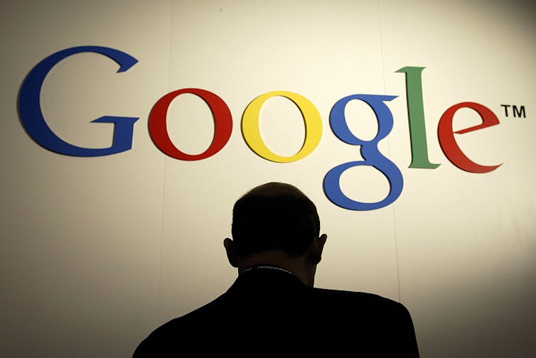 A figure stands under a Google sign.