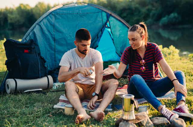 Couple camping applying insect repellant
