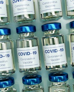 Vials labelled 'COVID-19 Coronavirus Vaccine' lined up in rows.