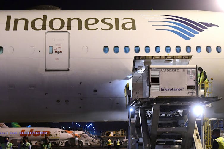 Workers unload a container containing the Sinovac vaccine at an Indonesian airport