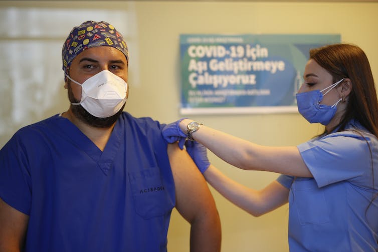 A person receiving a vaccine by a health-care worker