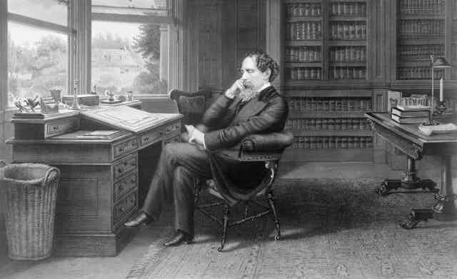 A black and white image of Charles Dickens sitting in his study.