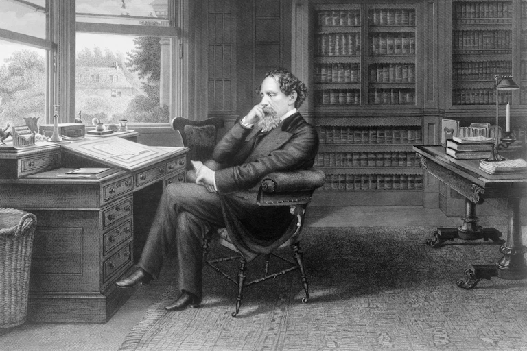 A black and white image of Charles Dickens sitting in his study.
