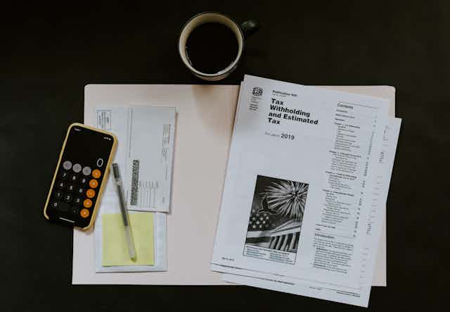 A phone and some tax documents on a table with a cup of coffee
