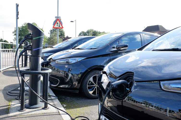 Three electric cars in a line connected to charging points.