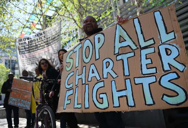 Man holding sign that says "stop all charter flights"