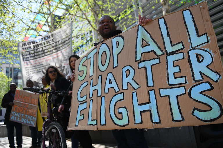 Man holding sign that says "stop all charter flights"