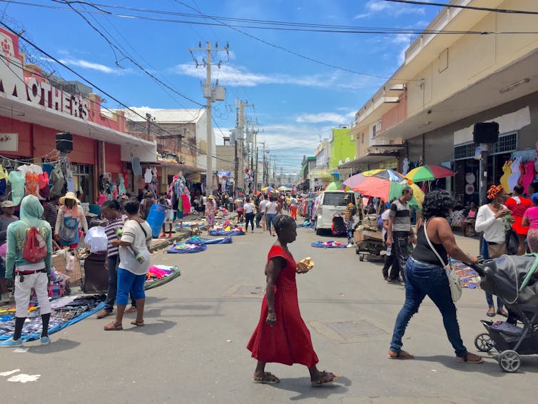 Woman in red crossing road on busy street in Kingston Jamaica