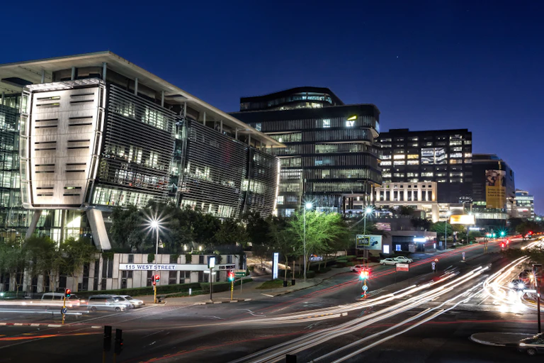 City street at night with brightly lit modern buildings.