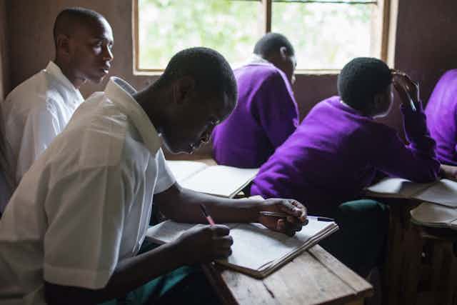 Ugandan students take notes in class.