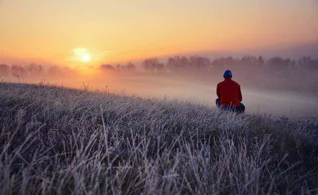 Man watching sunrise in nature during winter.