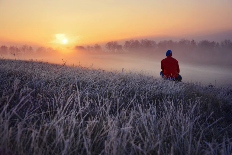 Man watching sunrise in nature during winter.