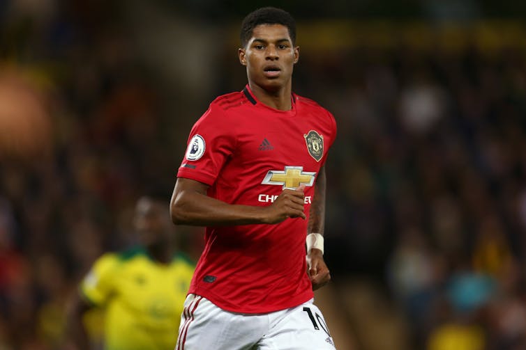 Manchester United player Marcus Rashford running on the pitch.