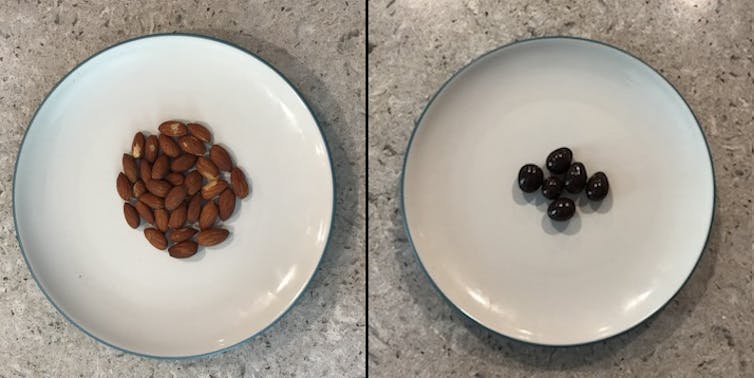 A plate of almonds next to a plate of a smaller quantity of chocolate-covered almonds