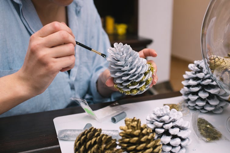 Woman painting pine cones for Christmas