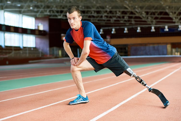 Man in sportswear at running track with prosthetic blade.