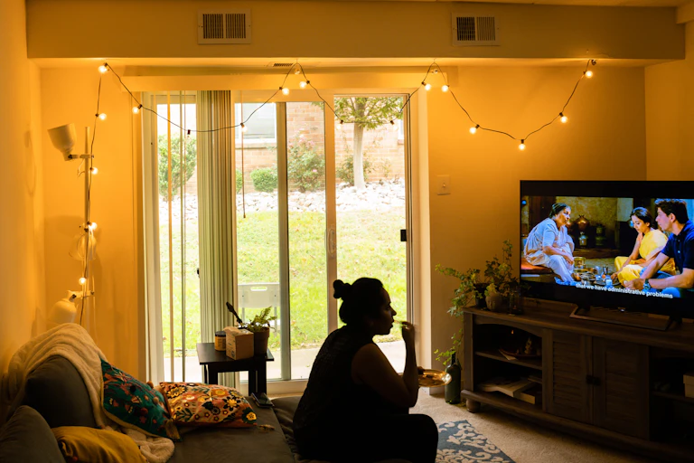A woman sits in front of the TV, watching a show.