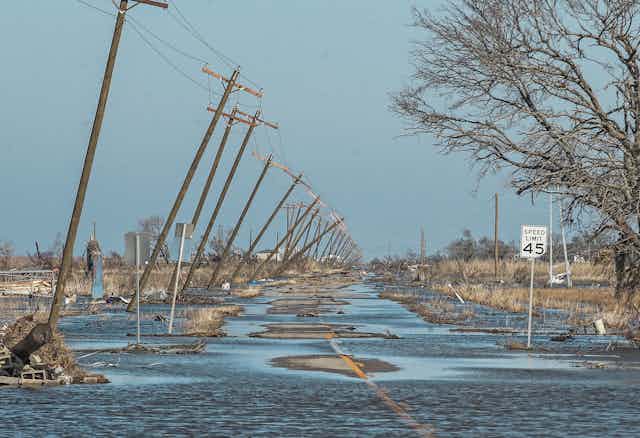 A flooded road lined by collapsing pylons